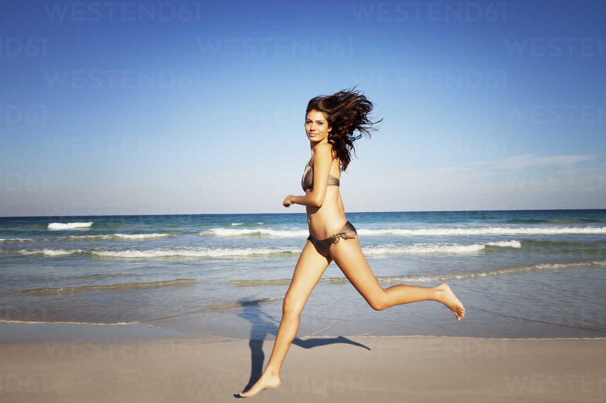 Female Running On Beach Over Beautiful Sky Stock Photo, Picture