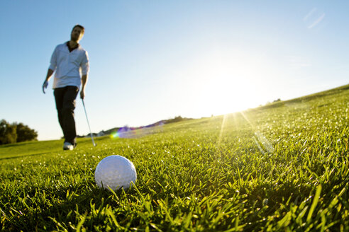 Mann steht auf einem Golfplatz vor klarem Himmel - CAVF01900