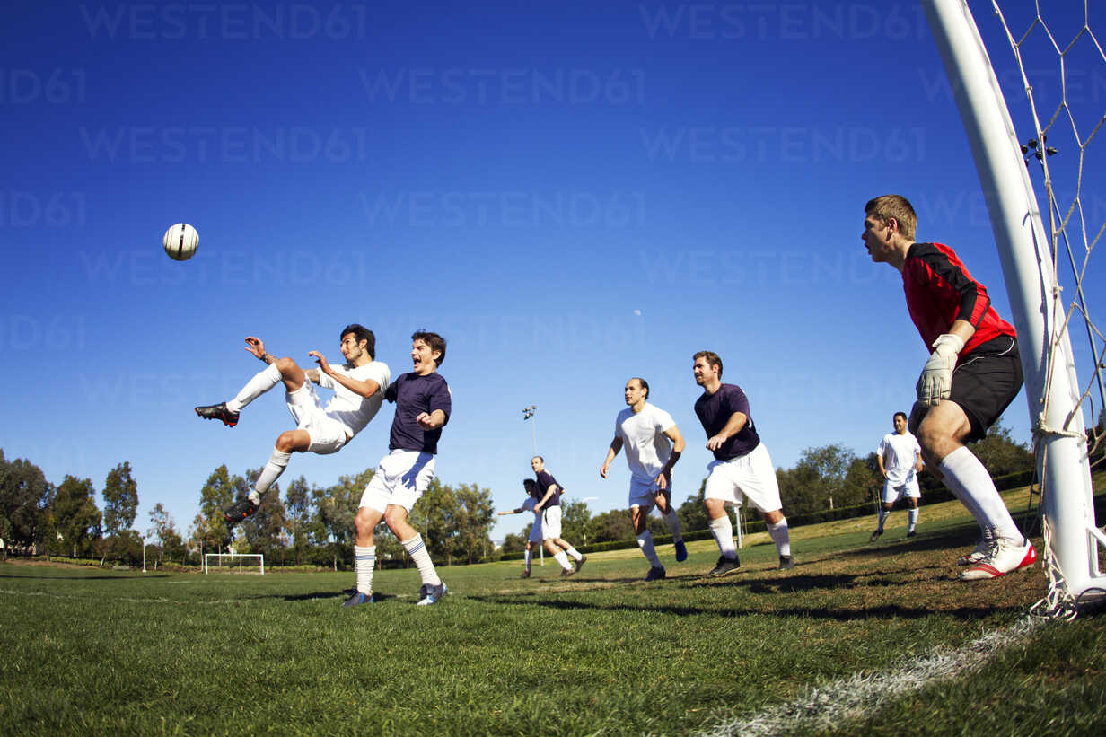 Freunde spielen Fußball auf einem Feld, lizenzfreies Stockfoto