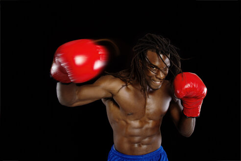 Porträt eines Mannes mit Boxhandschuhen vor einem schwarzen Hintergrund - CAVF01916