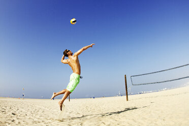 Mann schlägt Ball am Strand gegen klaren Himmel - CAVF01920