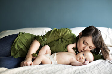 Mutter küsst Tochter auf dem Bett liegend - CAVF01973