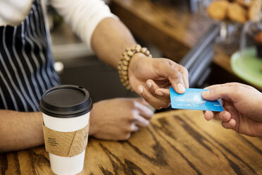 High angle view of man giving debit card to owner at cafe - CAVF02000