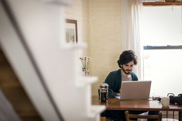 Mann, der einen Laptop benutzt, während er zu Hause sitzt - CAVF02056