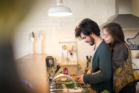 Seitenansicht eines in der Küche stehenden Paares, lizenzfreies Stockfoto