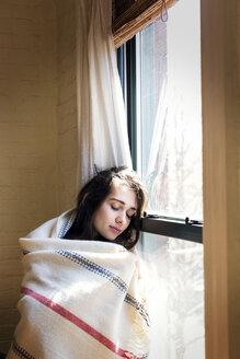Frau mit geschlossenen Augen, die sich zu Hause ans Fenster lehnt - CAVF02071