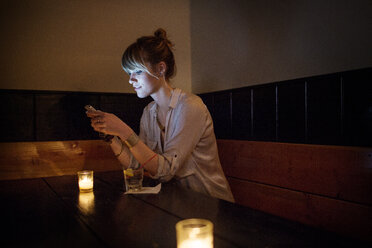 Woman using smart phone while sitting in bar - CAVF02131