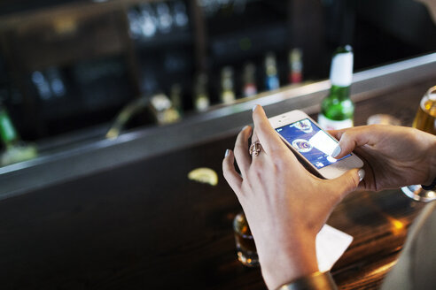 Hohe Winkelansicht einer Frau, die Alkohol auf einem Tisch in einer Bar fotografiert - CAVF02132