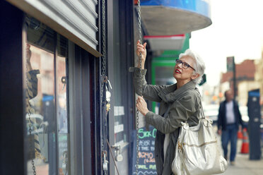 Frau beim Öffnen eines Ladenladens - CAVF02140