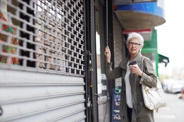 Frau schaut weg, während sie vor einem Geschäft steht - CAVF02141