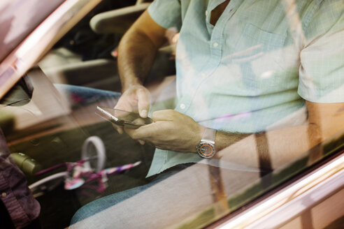 Hohe Winkel Ansicht des Mannes mit Smartphone während der Fahrt im Auto durch das Fenster gesehen - CAVF02233