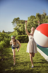 Fröhliche Freunde spielen mit Ball im Hinterhof an einem sonnigen Tag - CAVF02279