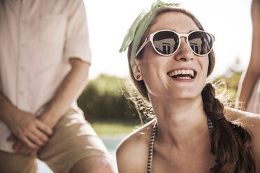 Glückliche Frau mit Sonnenbrille im Hinterhof an einem sonnigen Tag - CAVF02284