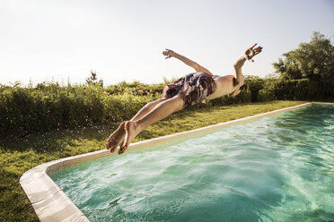 Man jumping into swimming pool against clear sky - CAVF02289