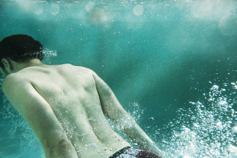Rückansicht eines unter Wasser schwimmenden Mannes, lizenzfreies Stockfoto