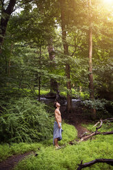 Seitenansicht eines Mannes, der im Wald steht und nach oben schaut - CAVF02351