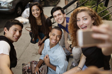 High angle view of woman taking selfie with friends while sitting on steps - CAVF02393