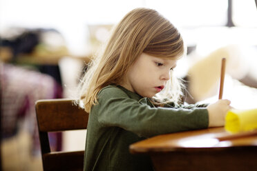 Girl writing while sitting at table in home - CAVF02401