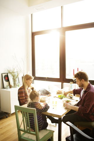 Glückliche Familie frühstückt am Esstisch im Haus, lizenzfreies Stockfoto