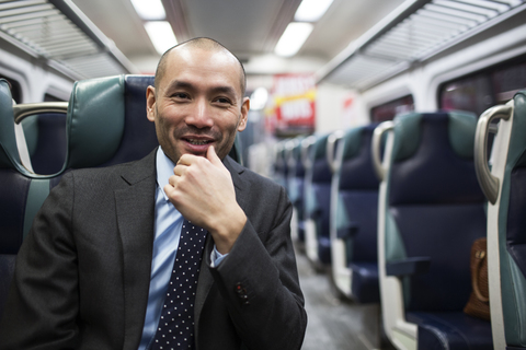 Glücklicher Geschäftsmann, der während der Fahrt in der U-Bahn wegschaut, lizenzfreies Stockfoto