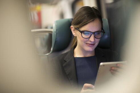 Glückliche Geschäftsfrau mit Tablet während der Fahrt in der U-Bahn - CAVF02468