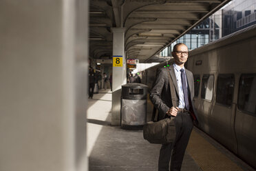 Businessman looking away while standing at subway platform - CAVF02470