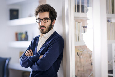 Portrait of confident man with arms crossed leaning on wall at home - CAVF02522