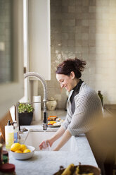 Seitenansicht einer Frau beim Geschirrspülen zu Hause - CAVF02557