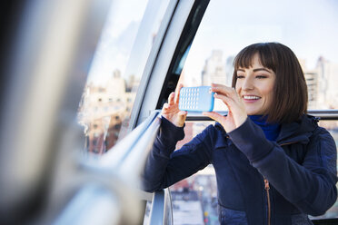 Frau beim Fotografieren mit dem Smartphone während der Fahrt im Zug - CAVF02570