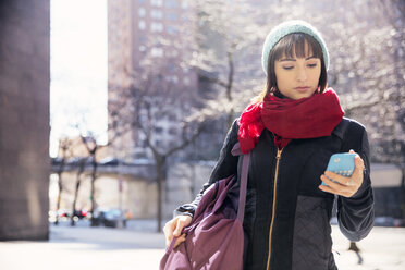 Frau benutzt Smartphone, während sie auf der Straße in der Stadt steht - CAVF02583