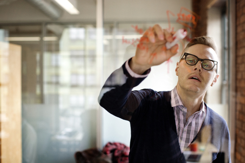 Man writing plan on glass in office stock photo