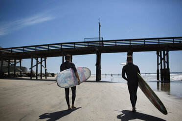 Rückansicht von Männern mit Surfbrettern am Strand - CAVF02649