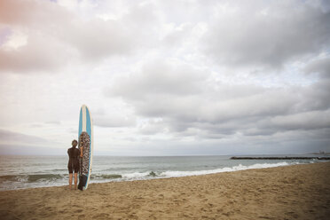 Rückansicht einer Frau mit Paddleboard am Strand gegen den Himmel - CAVF02677