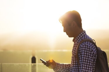 Seitenansicht eines Mannes, der ein Mobiltelefon benutzt - CAVF02721