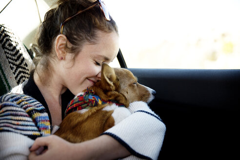 Frau umarmt Hund, während sie im Auto sitzt - CAVF02750