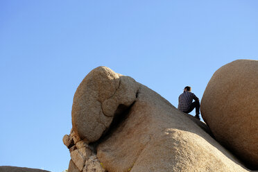 Rückansicht eines auf einem Felsen sitzenden Mannes - CAVF02756