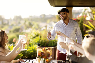 Freunde mit Weingläsern am Esstisch auf der Veranda - CAVF02782