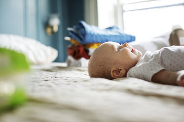 Oberflächenniveau eines glücklichen kleinen Mädchens auf dem Bett liegend - CAVF02841