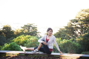 Young woman exercising on wood at field against sky - CAVF02924