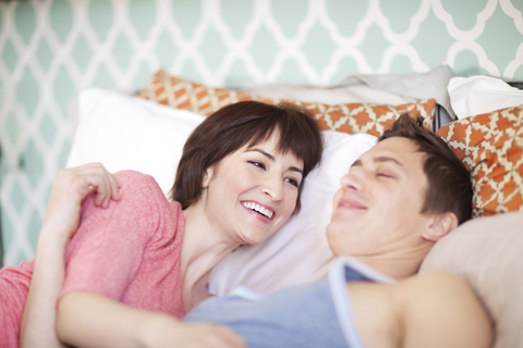 Glückliches Paar auf dem Bett liegend zu Hause, lizenzfreies Stockfoto