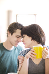 Frau trinkt Kaffee, während sie mit ihrem Freund zu Hause sitzt - CAVF02965