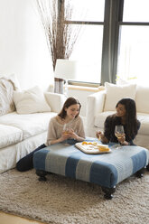 Hochformatige Ansicht von Freunden, die sich zu Hause bei Snacks und Wein entspannen - CAVF02985