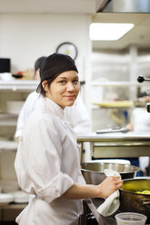 Porträt einer glücklichen Köchin bei der Zubereitung von Speisen in einer Großküche - CAVF03033