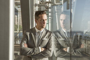 Thoughtful businessman leaning on glass wall - CAVF03041