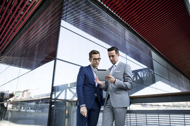 Business colleagues using tablet computer while standing against modern building - CAVF03076