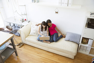 Hohe Winkelansicht von Freunden, die einen Laptop benutzen, während sie zu Hause auf der Couch sitzen - CAVF03115