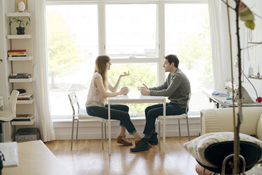 Colleagues discussing while having coffee at table in office - CAVF03121