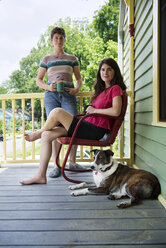 Porträt einer Frau mit Hund auf einer Veranda - CAVF03179