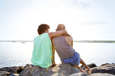 Rear view of couple sitting at lakeshore - CAVF03193