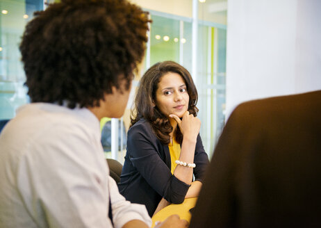 Geschäftsfrau schaut ihre Kollegen an, während sie im Büro sitzt - CAVF03207